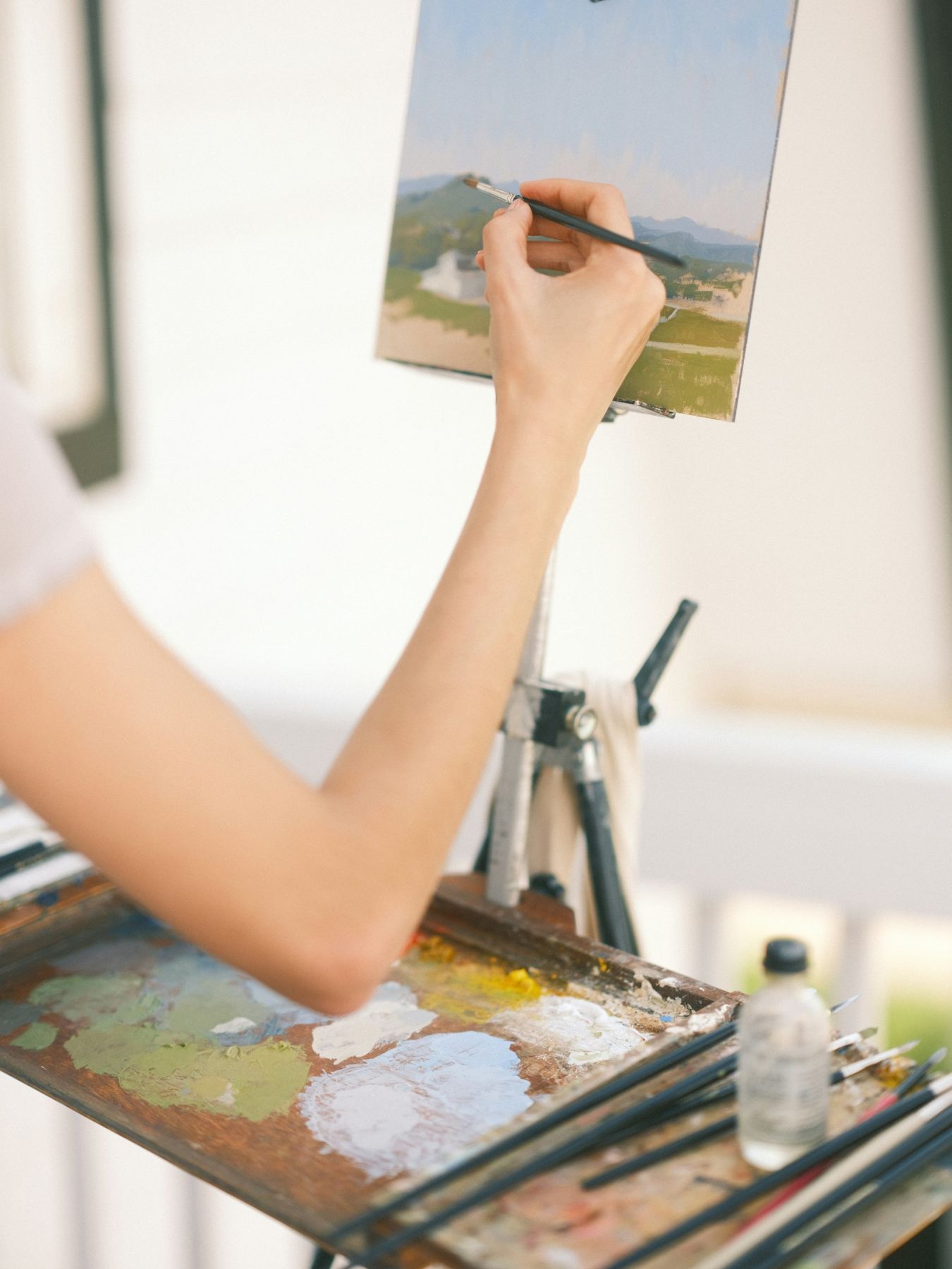 An artist painting a landscape at an easel