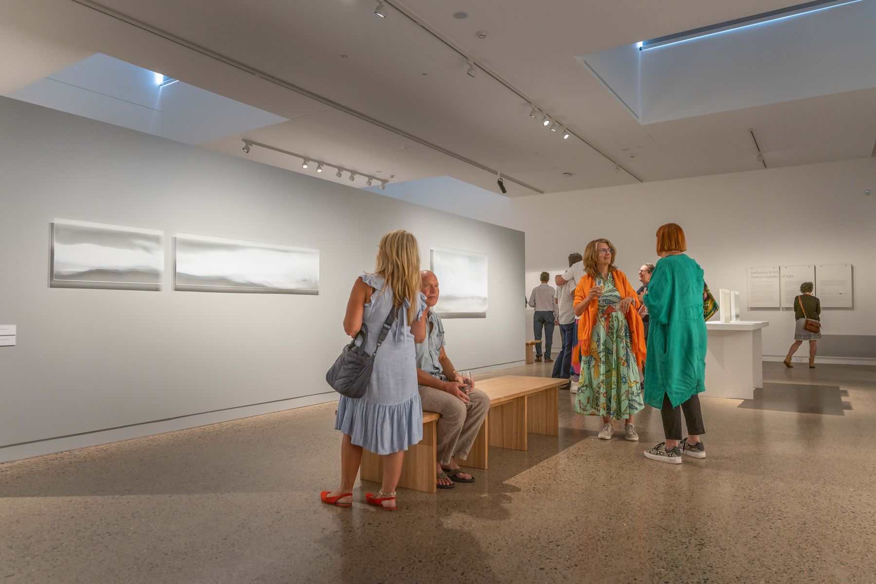 Visitors talking in a gallery among works on the walls