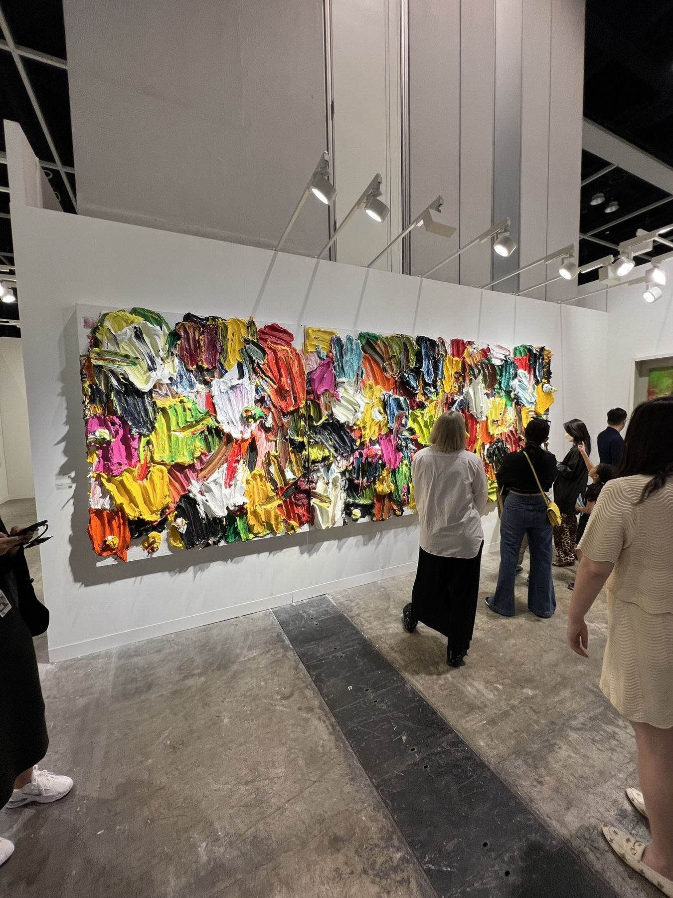 Visitors in front of a large, brightly coloured wall work at an art fair