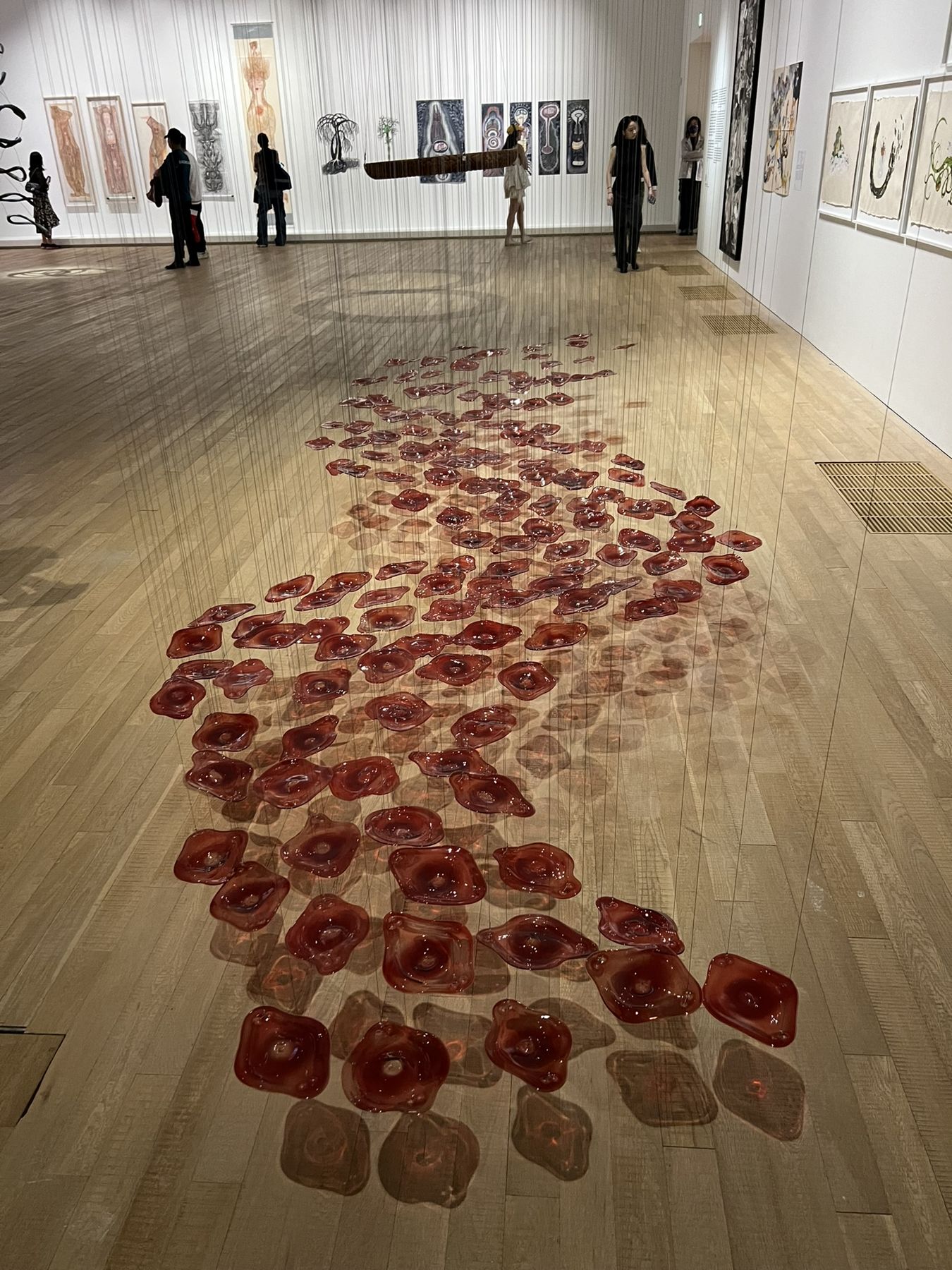 A floor installation of red glass forms stretching across a gallery at Tai Kwun, Hong Kong