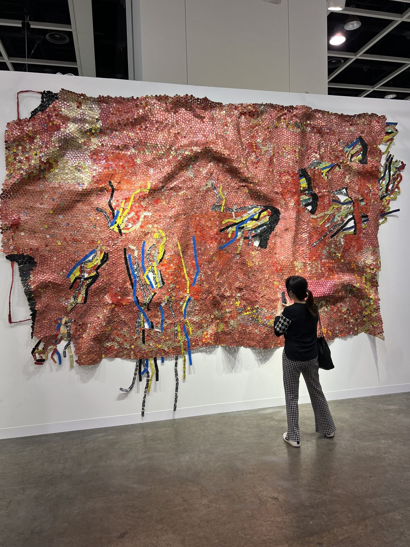 A visitor studying a large textile work at an art fair