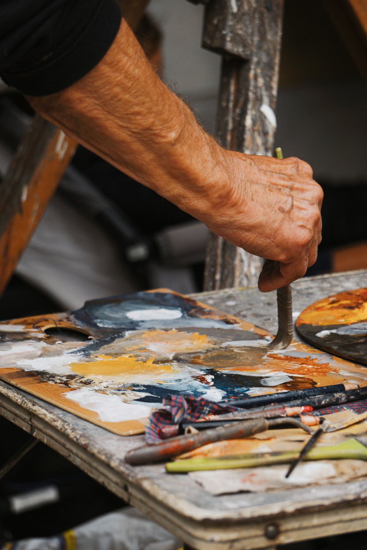 A hand mixing paint on a well-used palette