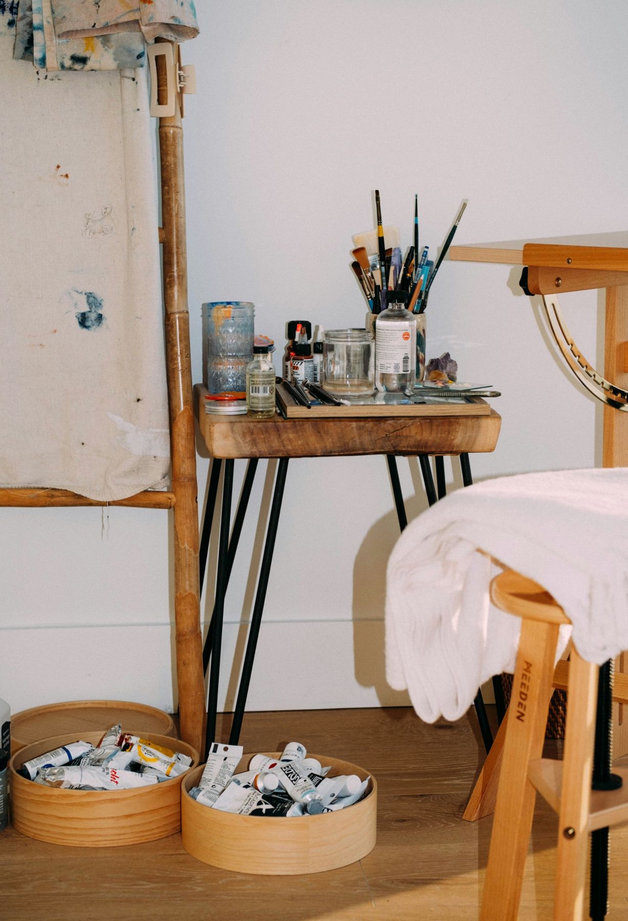 A studio corner with brushes, jars and paint tubes